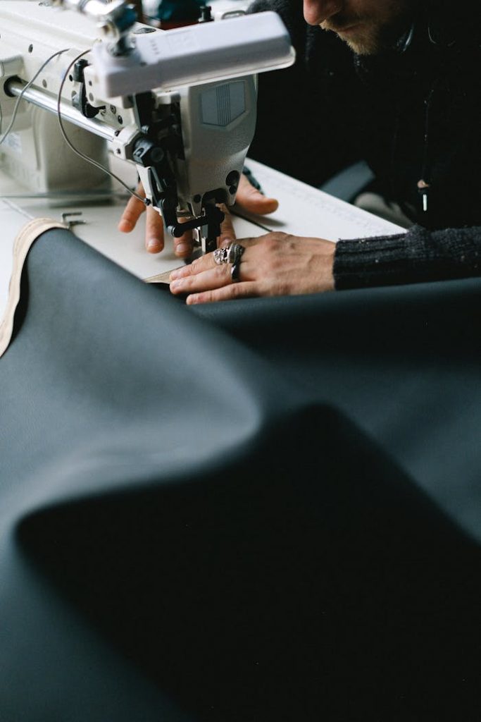 A tailor working with a sewing machine, crafting fabric in a focused environment.